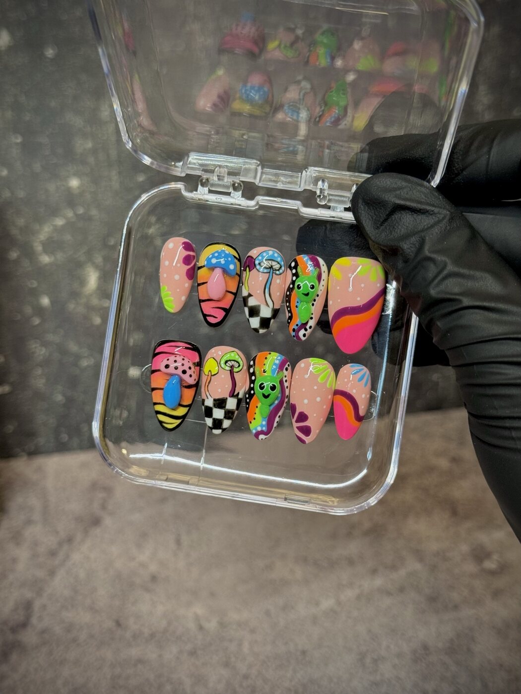Almond press-on nails with neon mushrooms, green aliens, rainbow waves and checkerboard art